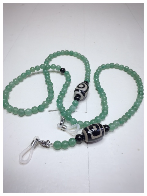 Łańcuszek do okularów z kamieni w kolorze zielonym z czarno białym dodatkiem na lnianej torebce opakunkowej.