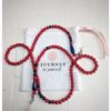 A chain for glasses made of red stones with navy blue accessories on a linen bag.