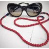 A chain for glasses made of red stones with navy blue accessories on a linen bag.