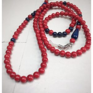 A chain for glasses made of red stones with navy blue accessories on a linen bag.