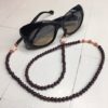 A chain for glasses made of maroon stones with beige stars between orange stones.