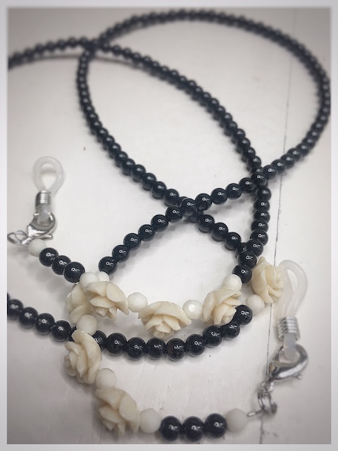 A chain for glasses made of black stones with cream roses and pebbles between them.