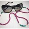 A chain for glasses made of fuchsia-colored stones with white and turquoise accessories.