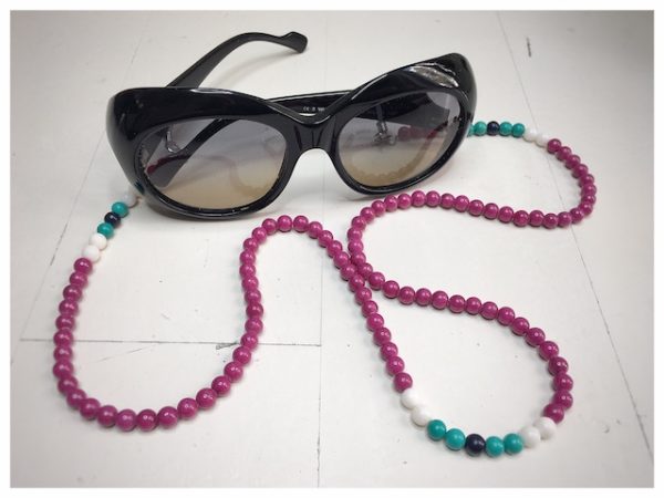 A chain for glasses made of fuchsia-colored stones with white and turquoise accessories.