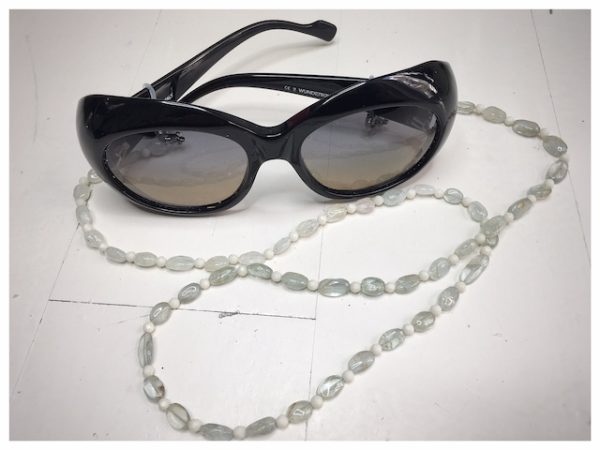 A chain for glasses made of blue glass stones and beige between them.