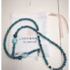 A chain for glasses of turquoise color with a white-turquoise larger stone on a linen packaging bag.