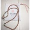 A chain for glasses made of cocoa-colored stones with cream roses and black pebbles between them.