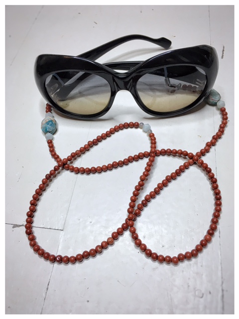 Łańcuszek do okularów „Wzmocnienie” to obrazek łańcuszka z kamieni naturalnych w kolorze rdzawym z turkusowymi dodatkami z okularami.