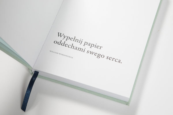 Dziennik Snów to zdjęcie seledynowego notatnika oprawionego w płótno na białym tle.